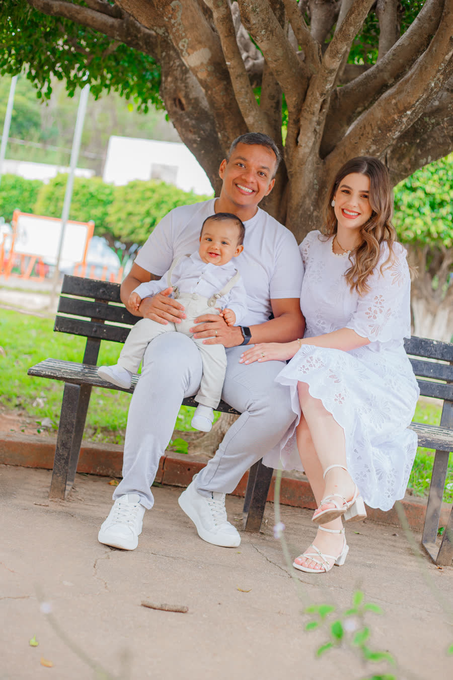 Thais Trindade com o marido e o filho Vicente sentados num banco